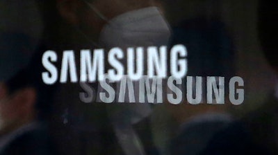 In this Wednesday, April 28, 2021 file photo employees are reflected on a revolving door windows with logos of the Samsung Electronics Co. at its office in Seoul, South Korea.