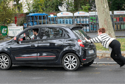 A woman pushes her car to reach a gas station, Friday, Oct. 14, 2022 in Nanterre, outside Paris.