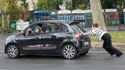 A woman pushes her car to reach a gas station, Friday, Oct. 14, 2022 in Nanterre, outside Paris.