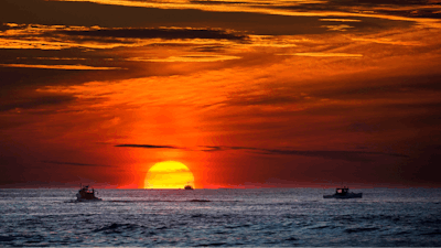 Lobster fishermen work at sunrise in the Atlantic Ocean, Sept. 8, 2022, off of Kennebunkport, Maine.