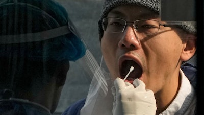 A medical worker collects a sample from a man at a coronavirus testing site in Beijing, Wednesday, Nov. 2, 2022.