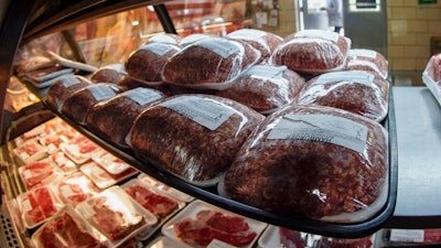 In this photo made on Thursday, June 16, 2022, rows of fresh meat is seen through the display coolers as a woman enters the retail section at the Wight's Meat Packing facility in Fombell, Pa.