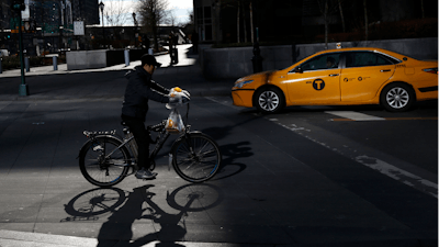 A man making deliveries rides an electronic bike in New York, Dec. 21, 2017.