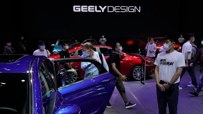 Visitors look at cars produced by Geely at the Auto China 2020 show in Beijing on Sept. 27, 2020.