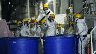 Men in hazmat suits work inside a facility with equipment to remove radioactive materials from contaminated water at the Fukushima Daiichi nuclear power plant, run by Tokyo Electric Power Company Holdings (TEPCO), in Okuma town, northeastern Japan, Thursday, March 3, 2022.