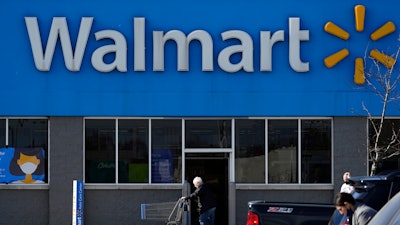 In this Nov. 5, 2020 file photo, a woman pushes a shopping cart to enter a Walmart in Rolling Meadows, Ill.