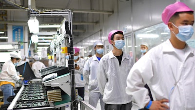 Workers line up to get tested for COVID-19 at the Foxconn factory in Wuhan in central China's Hubei province on Aug. 5, 2021. Employees at the world's biggest Apple iPhone factory have been beaten and detained in protests over contract disputes amid anti-virus controls, according to employees and videos posted on social media Wednesday, Nov. 23, 2022. Videos on Chinese social media that said they were filmed at the factory in the central city of Zhengzhou showed thousands of people in masks facing rows of police in white protective suits with plastic riot shields.