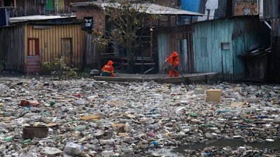 City workers remove garbage floating on the Negro River, Manaus, Brazil, June 6, 2022.