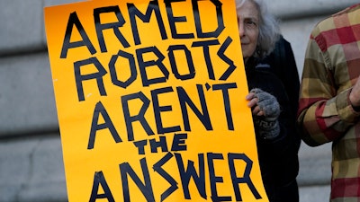 Diana Scott holds up a sign while taking part in a demonstration about the use of robots by the San Francisco Police Department outside of City Hall in San Francisco, Monday, Dec. 5, 2022.