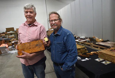 Fred Holabird, left, and Bob Evans pose with artifacts including a Wells Fargo treasure box lid from the S.S. Central America in a warehouse in Sparks, Nevada, on May 4, 2022. The lid, which sold for $99,600, was among 270 Gold Rush-era artifacts that sold for a total of nearly $1 million in Reno last weekend, according to Holabird Western American Collections.