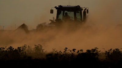Dust flies as a farmer plows over a failed cotton field, Oct. 4, 2022, Halfway, Texas.