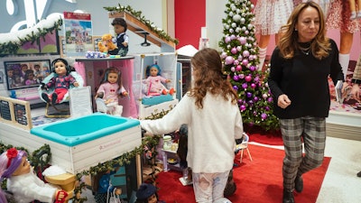 Jamie Cygielman, right, general manager and president at American Girl, leaves a youngster browsing the company's latest holiday showcase doll set, Friday, Dec. 2, 2022, in New York. Cygielman said roughly half its sales went to adults after a relaunch of the first six American Girl dolls in May 2021 to celebrate its 35th anniversary.