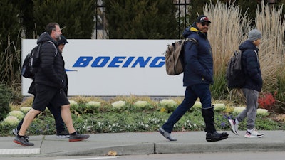 Workers walk past a Boeing Co. sign as they leave the factory where the company's 737 Max airplanes are built, Dec. 17, 2019, in Renton, Wash.