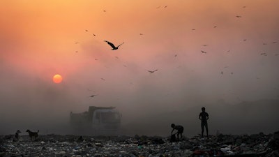 A thick blanket of smoke envelops young ragpickers searching for reusable material at a garbage dump in New Delhi, India.