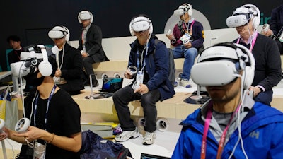 Attendees wear VR headsets while previewing the Caliverse Hyper-Realistic Metaverse experience at the Lotte booth during the CES tech show Friday, Jan. 6, 2023, in Las Vegas.