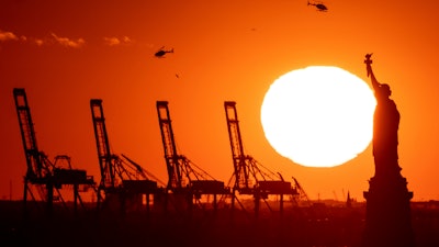 Container cranes at a port in New Jersey behind the Statue of Liberty, Nov. 20, 2022.