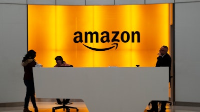 In this Feb. 14, 2019 file photo, people stand in the lobby for Amazon offices in New York. Amazon is ending a charity donation program it ran for a decade in its latest cost-cutting move. In a blog post on Wednesday, Jan. 18, 2023, the company said the program, called AmazonSmile, will shut down by February 20.