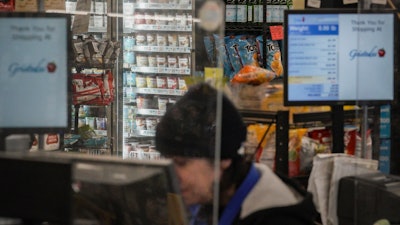 A cashier at a Gristedes supermarket in view of a freezer holding Haagen-Dazs ice cream, New York, Jan. 31, 2023.