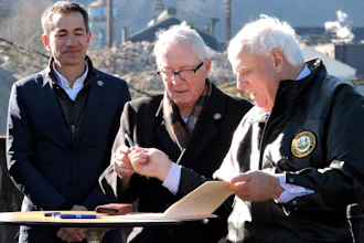 West Virginia Gov. Jim Justice, right, hands a pen used to sign House Bill 2882 to Weirton Mayor Harold 'Bubba' Miller, while Form Energy CEO Mateo Jaramillo watches.