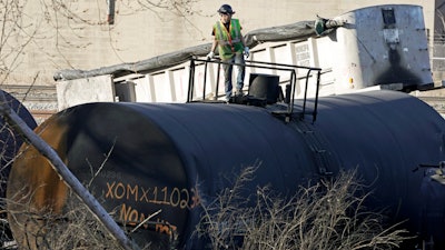 A cleanup worker stands on a derailed tank car of a Norfolk Southern freight train in East Palestine, Ohio, continues, Feb. 15, 2023.