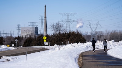 People walk on a trail at the Montissippi County Park near the Xcel Energy Monticello Generating Plant, a nuclear power plant, in Monticello, Minn., on Friday, March 24, 2023.