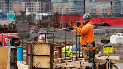 A construction worker prepares a recently poured concrete foundation, March 17, 2023, Boston.