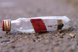 An empty miniature bottle that once contained liquor rests on a street near a sidewalk, Monday, April 3, 2023, in Boston.