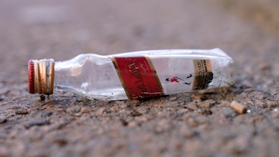 An empty miniature bottle that once contained liquor rests on a street near a sidewalk, Monday, April 3, 2023, in Boston.