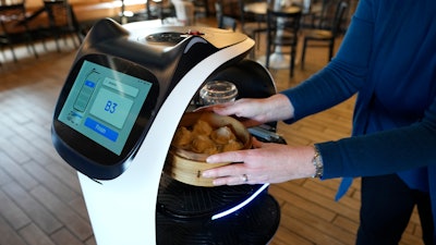 A customer receives a meal delivered by a BellaBot robot at the Noodle Topia restaurant on Monday, March 20, 2023, in Madison Heights, Mich.