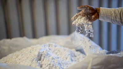 A worker stirs lithium with his hand at the SQM processing plant in Antofagasta, Chile, Wednesday, April 19, 2023.
