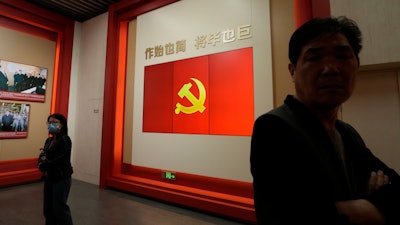 Visitors stand near a flag of the Chinese Communist Party at an exhibition in Shanghai, Thursday, April 20, 2023.