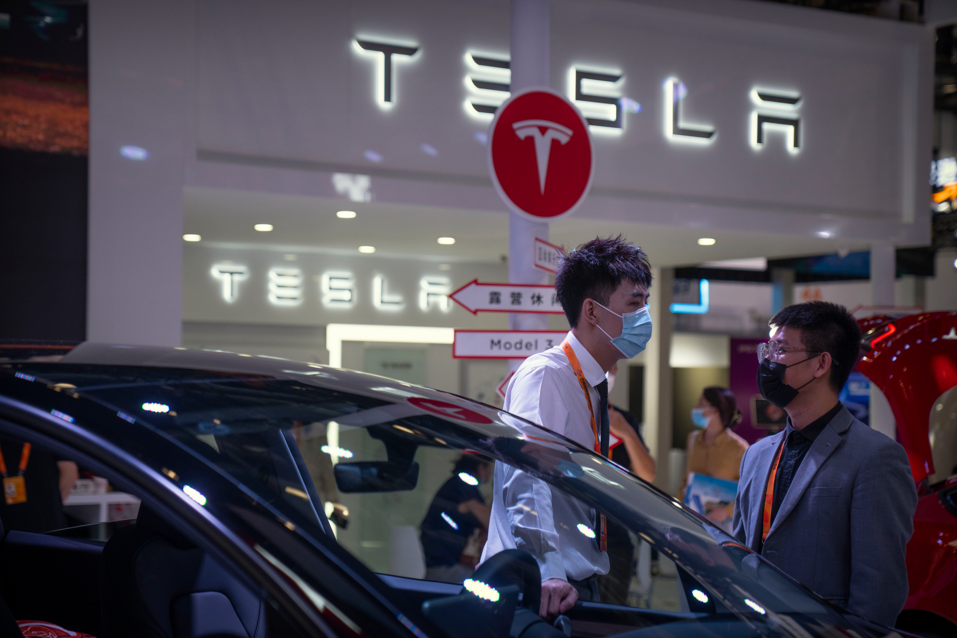 Staff members talk near vehicles at a display for automaker Tesla at the China International Fair for Trade in Services (CIFTIS) in Beijing on Sept. 2, 2022.