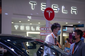 Staff members talk near vehicles at a display for automaker Tesla at the China International Fair for Trade in Services (CIFTIS) in Beijing on Sept. 2, 2022.