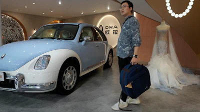 A visitor stands near a display of a car from Ora at the Auto Shanghai 2023 show in Shanghai, Wednesday, April 19, 2023.