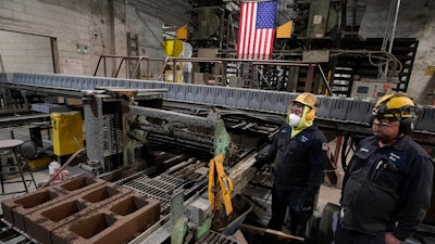 Workers monitor a production line of concrete blocks created with liquid carbon dioxide as an ingredient at the Glenwood Mason Supply Company, Tuesday, April 18, 2023, in the Brooklyn borough of New York. New York is forcing buildings to clean up, and several are experimenting with capturing carbon dioxide, cooling it into a liquid and mixing it into concrete where it turns into a mineral.