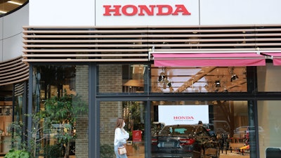 A woman walks past the logo of Honda Motor Co. in Tokyo on Oct. 19, 2021.