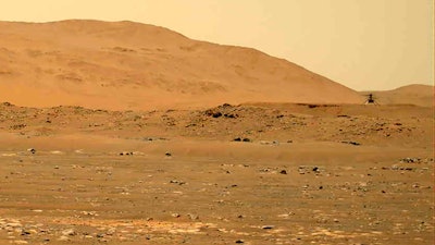 In this April 30, 2021, file image taken by the Mars Perseverance rover and made available by NASA, the Mars Ingenuity helicopter, right, flies over the surface of the planet.