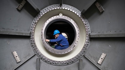 In this photo released by Xinhua News Agency, a worker measures the size of an equipment at Harbin Turbine Company Limited of Harbin Electric Corporation in Harbin in northeastern China's Heilongjiang Province on Friday, April 28, 2023.