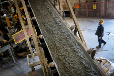 Fresh concrete is fed via a conveyor belt into a forming machine, producing blocks designed with liquid carbon dioxide as an ingredient at the Glenwood Mason Supply Company, Tuesday, April 18, 2023, in the Brooklyn borough of New York. New York is forcing buildings to clean up, and several are experimenting with capturing the carbon dioxide, cooling it into a liquid and mixing it into concrete where it turns into a mineral.