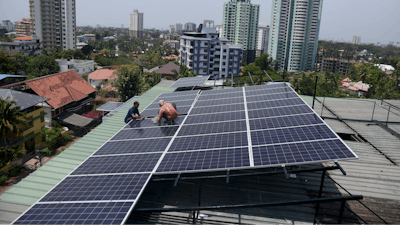 Workers install solar panels on the roof of a residential apartment in Kochi, southern Kerala state, India, March 22, 2023.