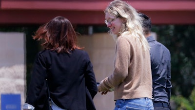 Disgraced Theranos CEO Elizabeth Holmes, center, is escorted by prison officials into a federal women's prison camp on May 30, 2023, in Bryan, Texas.