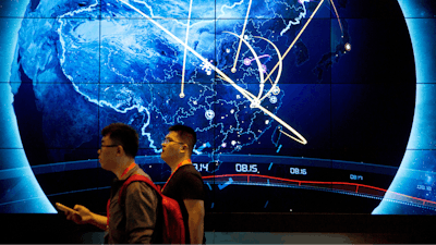 Attendees walk past an electronic display showing recent cyberattacks in China at the China Internet Security Conference in Beijing, on Sept. 12, 2017.