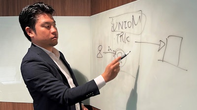 Yoshihito Hasegawa, who heads Tokyo-based TRK that runs a job-quitting service called Guardian, shows a diagram to explain what his service does at his office in Tokyo on June 21, 2023.