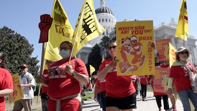 Fast food workers and their supporters march past the California state Capitol in Sacramento, Tuesday, Aug. 16, 2022.