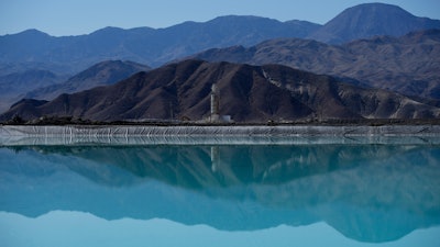 Mountains and a liming facility are reflected in a brine evaporation pond at Albemarle Corp.'s Silver Peak lithium facility, on Oct. 6, 2022, in Silver Peak, Nev.