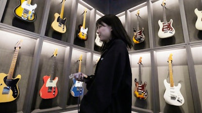 A staff member walks past Fender guitars on display at the opening ceremony of its Tokyo store Thursday, June 29, 2023.