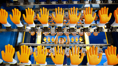 A laborer works on the production line for rubber gloves at a factory making work safety products in Gaomi in eastern China's Shandong Province, Saturday, June 17, 2023.