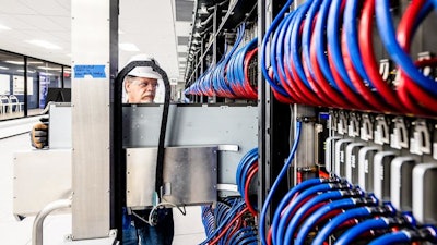 A technician installs Aurora’s blade, which is a sleek, rectangular unit that houses the supercomputer’s processors, memory, networking and cooling technologies.