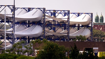 Giant wind turbine blades for the Vineyard Winds project are stacked on racks in the harbor, Tuesday, July 11, 2023, in New Bedford, Mass.