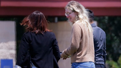 Disgraced Theranos CEO Elizabeth Holmes, center, is escorted by prison officials into a federal women's prison camp on May 30, 2023, in Bryan, Texas.